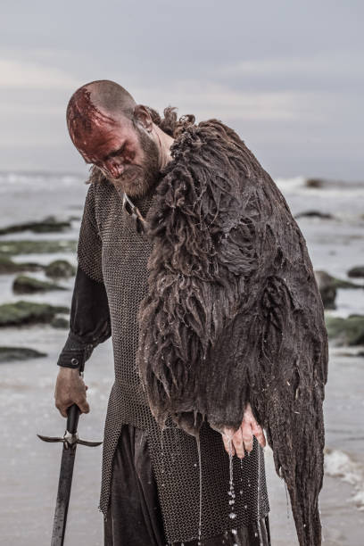 istock Weapon wielding bloody medieval warrior alone on a cold seashore 999123590