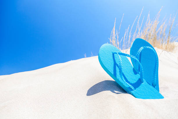 istock Summer, beach or holiday backgrounds: blue flip flops on white sand dune 999126420