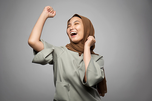 Excited young Muslim woman in white background