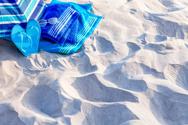 istock Summer, beach or holiday backgrounds: blue beach accessories on white sand dune 999132112