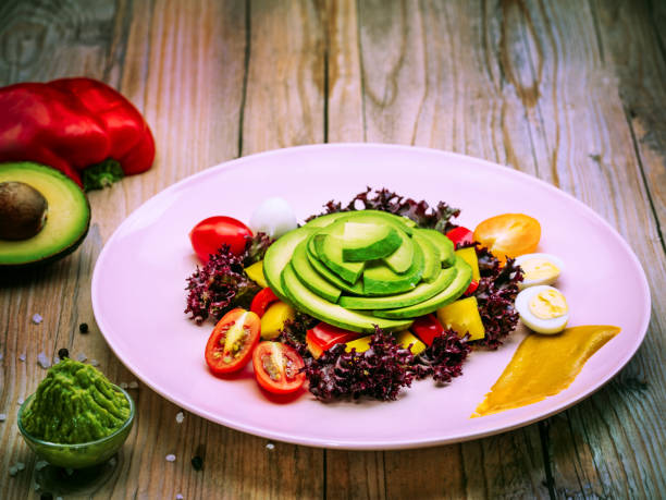 Dietary Avocado Salad With Cherry Tomatoes, Quail Eggs, Yellow And Red Pepper, Lettuce. Avocado Is Source Of Nutrition, Vitamin, Popular Food Product For Sport And Healthy Diet.