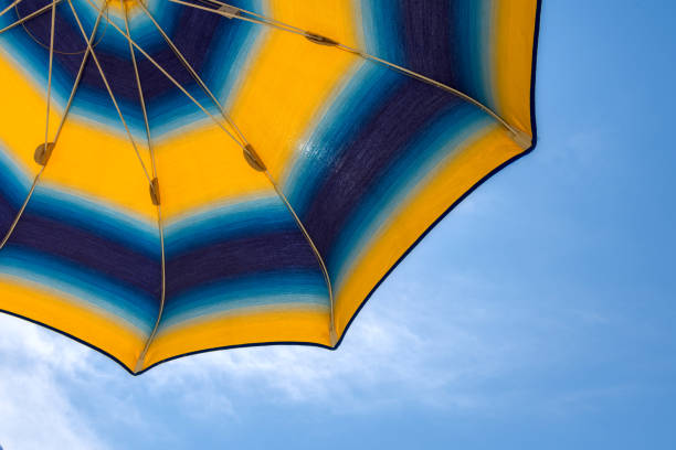 istock Bright yellow-blue beach umbrella with blue sky. 999150716