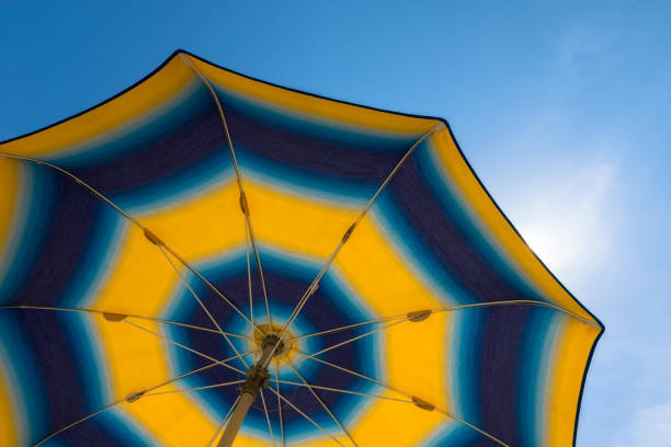 istock Bright yellow-blue beach umbrella with blue sky. 999150718