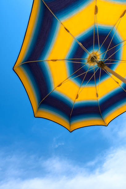 istock Bright yellow-blue beach umbrella with blue sky. 999150768