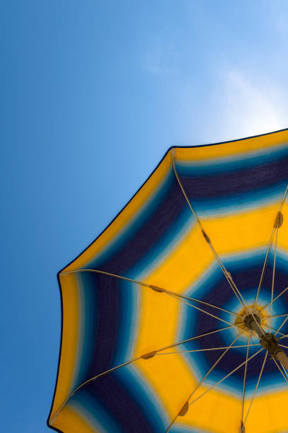 istock Bright yellow-blue beach umbrella with blue sky. 999150830