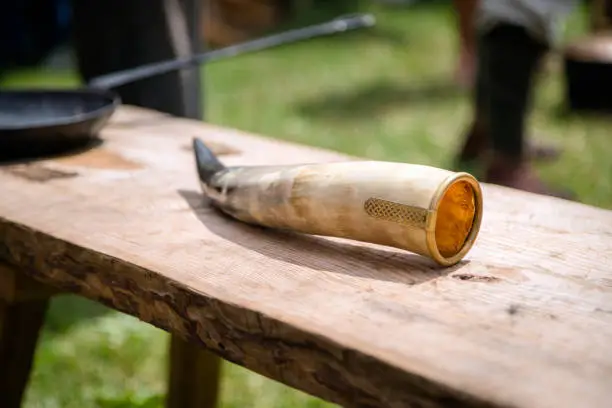 Photo of Decorated animal horn with metal engraving for wine vessel laying on wooden table