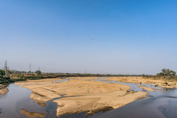istock Indian river with clean water in sandy bed  with power grid cable laying background. 999165506