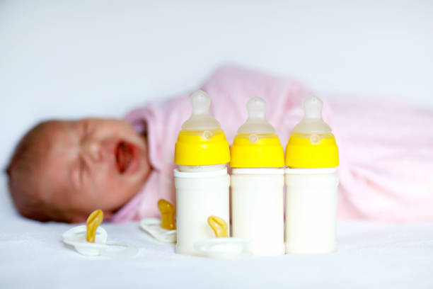 ボトルを看護と新生児の女の子が泣いています。赤ちゃんの数式を飲む。 - male nurse 写真 ストックフォトと画像
