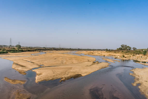 istock Indian river with clean water in sandy bed  with power grid cable laying background. 999190490