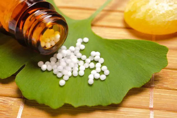 alternative medicine with homeopathic pills on ginkgo leaf