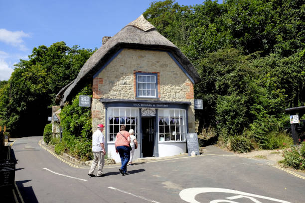 Godshill, Isle of Wight, UK. June 21, 2018.  Three senior holidaymakers walking towards a thatched tea rooms in the village of Godshill on the Isle of Wight, UK.