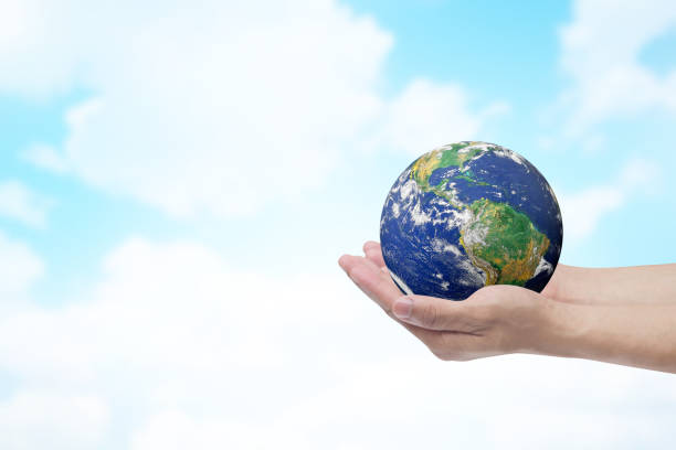 istock Two hands holding the earth in palm gesture on blurred blue sky color gradient background.Elements of this image furnished by NASA 999206820