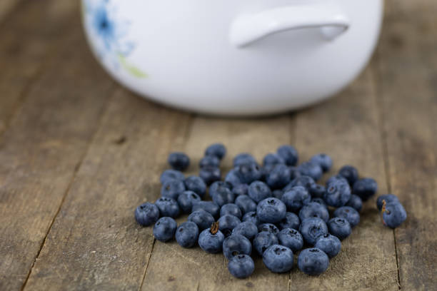 Ripe blueberry fruit in a container on a wooden kitchen table. Fruit prepared for dessert. Dark background.