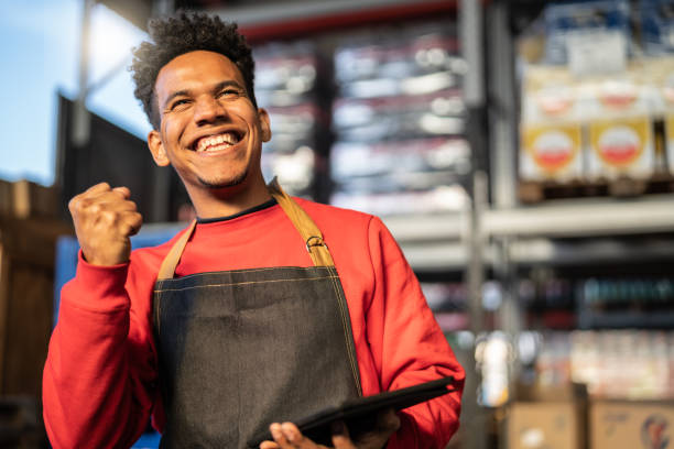 Man having good news on tablet at a warehouse