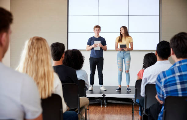 istock Students With Digital Tablets Giving Presentation To High School Class In Front Of Screen 999225994