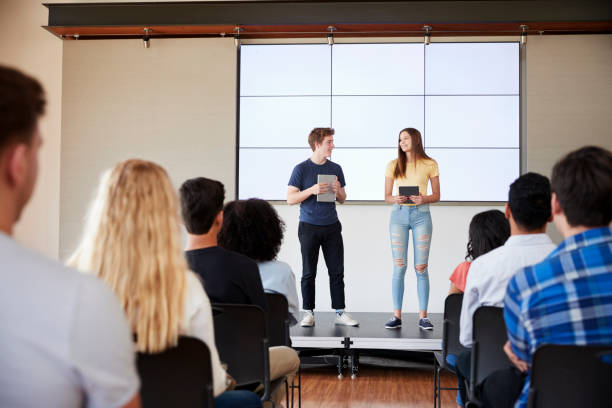 istock Students With Digital Tablets Giving Presentation To High School Class In Front Of Screen 999226152
