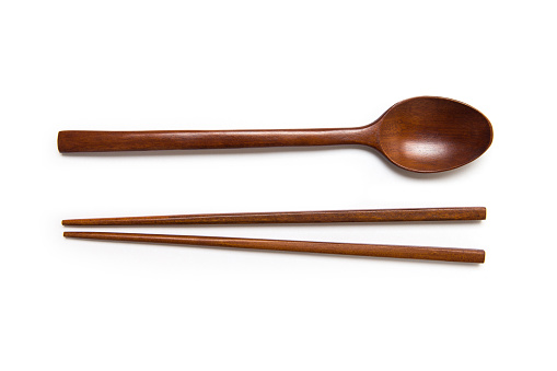 Wooden pairs of chopsticks and spoon isolated on white background.