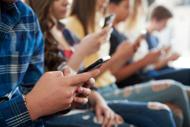 primo livello di una linea di studenti delle scuole superiori che utilizzano i telefoni cellulari - mobiles internet foto e immagini stock