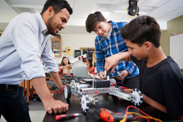 lehrer mit männlichen schüler gebäude roboterfahrzeug in wissenschaft lektion - science education child classroom stock-fotos und bilder