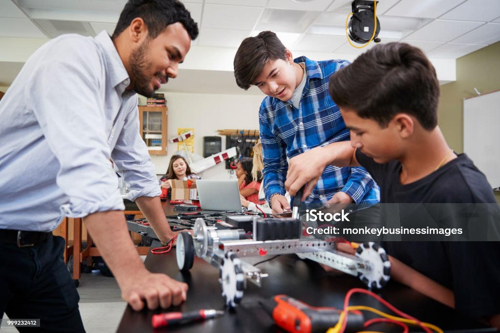 Professor com veículo robótico de edifício de alunos do sexo masculino na lição de ciência - Foto de stock de Professor royalty-free