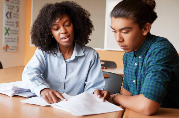 high school tutor giving male student one to one tuition at desk - teenager education teacher school imagens e fotografias de stock