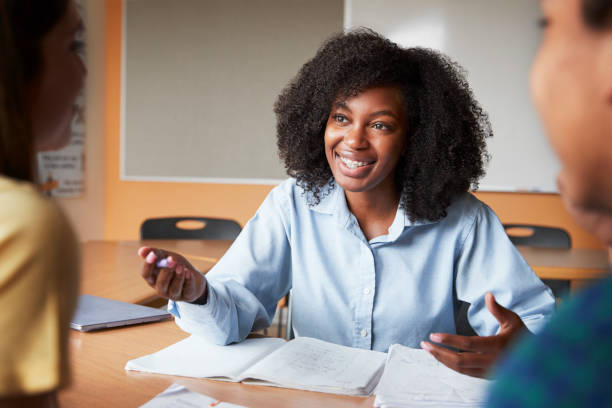 istock Female High School Tutor With Two Students At Desk In Seminar 999246430