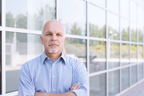 istock old  man standing with backdrop of business building 999254534