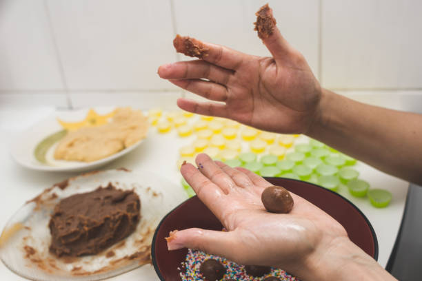 Woman hands preparing brigadeiro (handmade brazilian chocolate candy) Woman hands preparing brigadeiro. Handmade brazilian chocolate candy. Perspective view. Selective focus chocolate truffle making stock pictures, royalty-free photos & images
