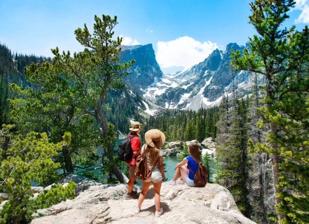 Family standing on top of the mountain enjoying  beautiful scenery. Family standing on top of the mountain enjoying  beautiful scenery. Early summer landscape with lake  and snow covered mountains.  Dream Lake, Rocky Mountains National Park, Colorado, USA. hallett peak stock pictures, royalty-free photos & images