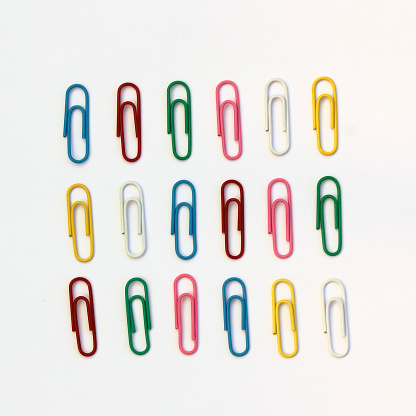 A flat lay of colourful paperclips on a white background.