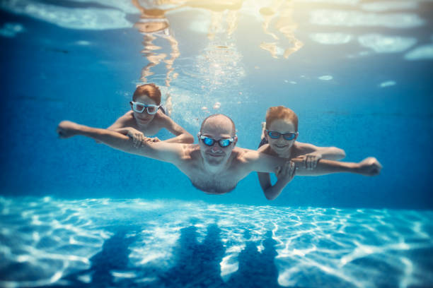 padre e figli che giocano sott'acqua nella piscina del resort - cheerful swimming pool happiness resort swimming pool foto e immagini stock