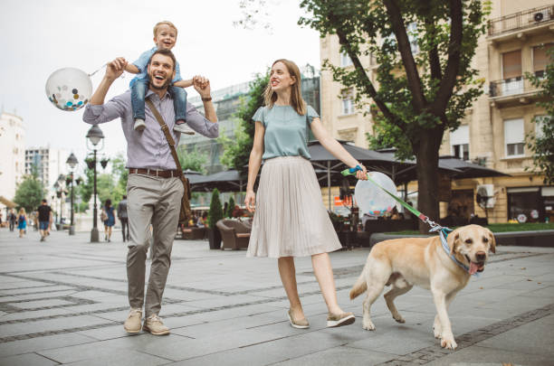 Always is fun when you spent time with family Family with one child outdoors on city street. Father carry son on piggyback, they enjoy in walk with their dog at summer. smart casual stock pictures, royalty-free photos & images