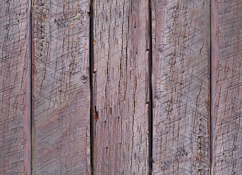 Weathered and scratched rustic wooden board.High angle view of a flat textured wooden board backgrounds. It has a beautiful nature and abstractive pattern. A close-up studio shooting shows details and lots of wood grain on the wood table. The piece of wood at the surface of the table also appears rich wooden material on it. The wood is dark brown color with darker brown lines and pattern on the bottom. Flat lay style. Its high-resolution textured quality.The close-up gives a direct view on the table, showing cracks and knotholes in the wood.