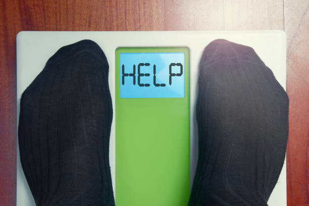 istock Closeup male feet on scale at morning Help word 999385016