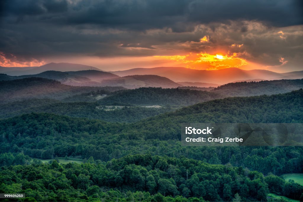 Summer Sun setting on the Blue Ridge Mountains in North Carolina Flat Rock overlook, just a 10 minute hike from the Blue Ridge Parkway.  Popular spot with locals to view a sunset. Blue Ridge Mountains Stock Photo