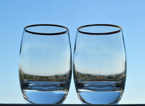 Two glasses with a thick bottom against the blue summer sky. It looks like glasses are filled with summer sky and sity