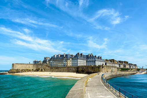 The walled city of Saint-Malo, France, with granite residential buildings protruding above the rampart and the Mole beach at the foot of the fortifications, seen from the breakwater.