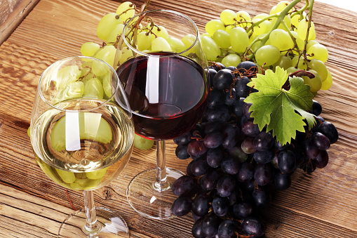 Red Wine and white wine with grapes and glasses on rustic background