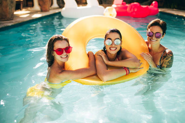 istock Cheerful women in pool with inflatable ring 999480408