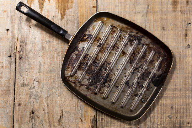 istock Dirty square frying pan on a table with rustic wood. 999489596
