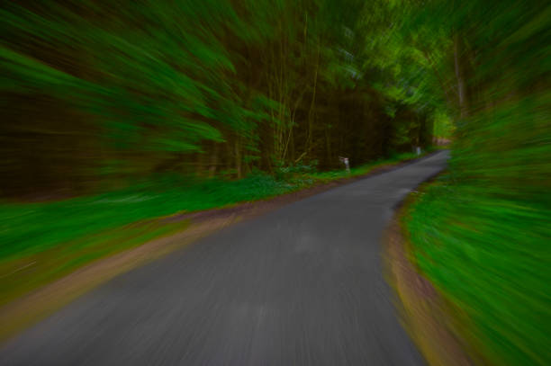 Car driving through forest on a curved road. Speed produces motion blurred images. Highly saturated