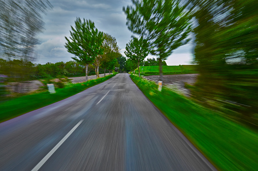 Car driving through forest on a curved road. Speed produces motion blurred images. Highly saturated