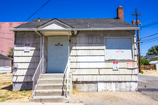 Abandoned One Story Home With Boarded Up Windows & Door