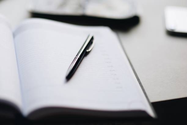 istock Close-Up Of Open Book With Pen On Table 999546912