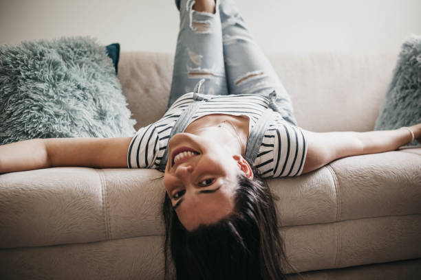 istock Beautiful young woman lying upside down on couch 999593578
