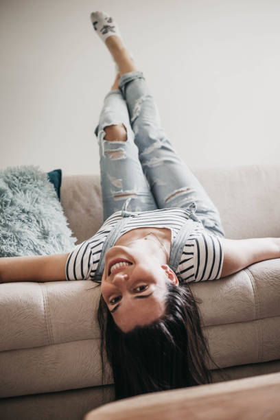 istock Beautiful young woman lying upside down on couch 999593656