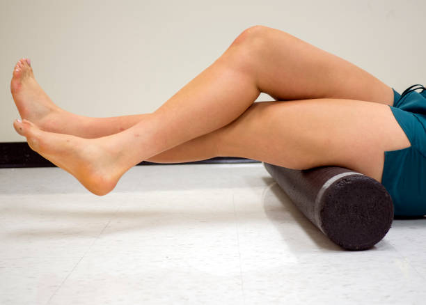 Varsity athlete using a foam roller to release her tight muscles Varsity athlete using a foam roller to release her tight muscles hamstring injury stock pictures, royalty-free photos & images