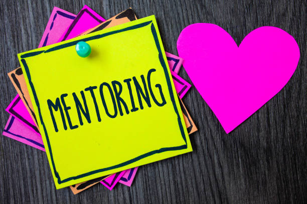 istock Handwriting text writing Mentoring. Concept meaning To give advice or support to a younger less experienced person Border sticky remember cards love heart pinned dark woody background. 999657336