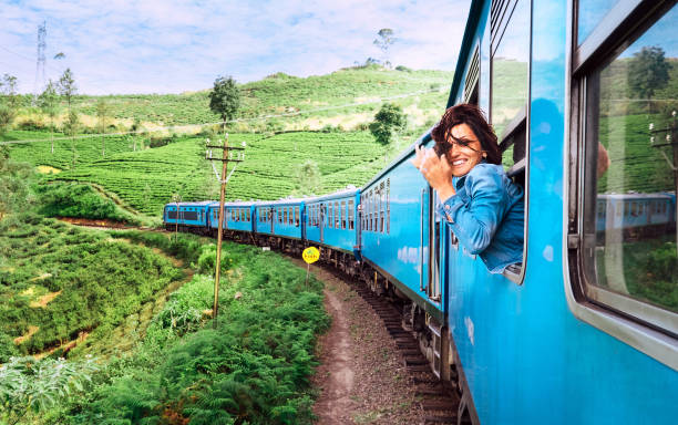 felice donna sorridente guarda fuori dalla finestra viaggiando in treno sulla strada ferroviaria più pittoresca dello sri lanka - tea island foto e immagini stock