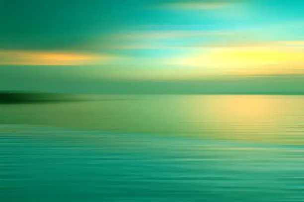 Motion blurred background of refraction in water. Panoramic dramatic view of Infinity sunset on the sea at twilight times.